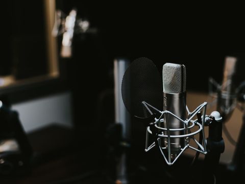 Studio condenser microphone with pop filter in a dark recording room