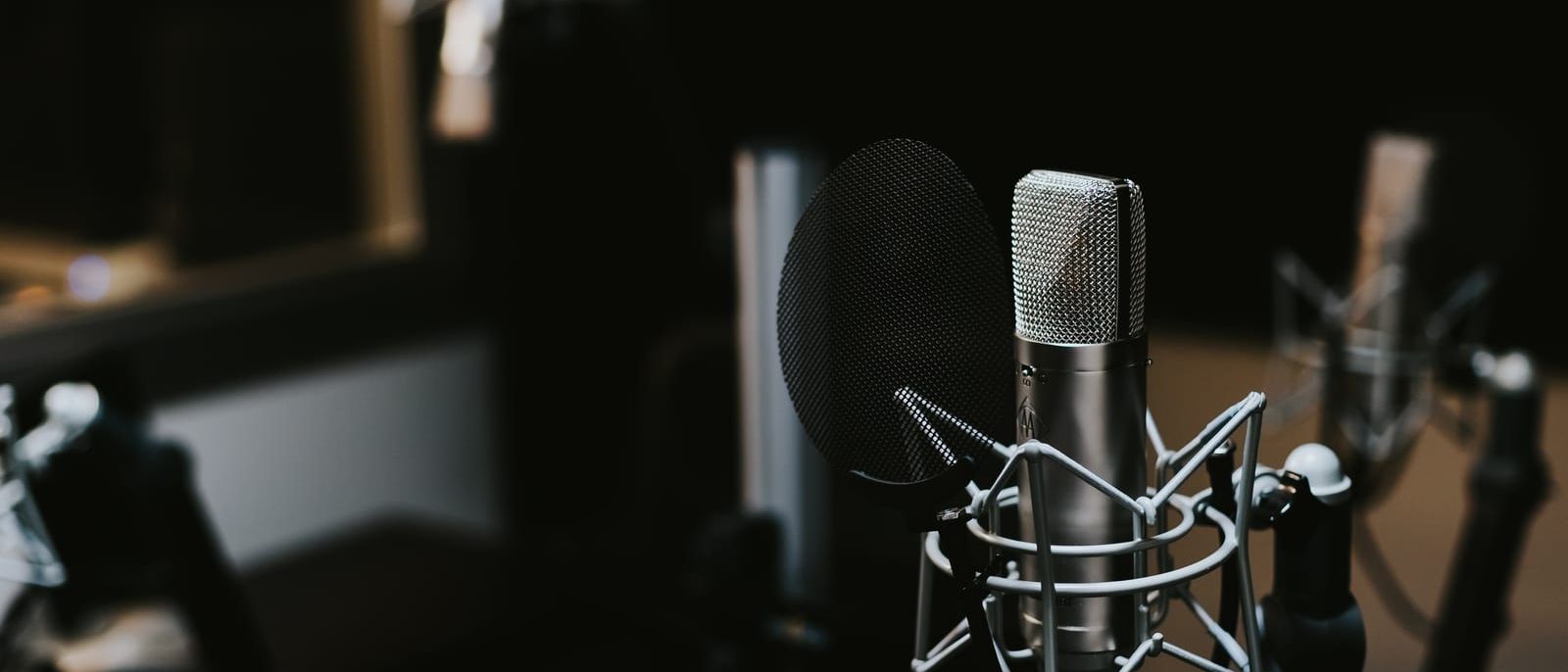 Studio condenser microphone with pop filter in a dark recording room
