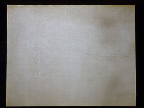 Sheet of laid paper on a light box showing a crowned crest watermark and a maker's name
