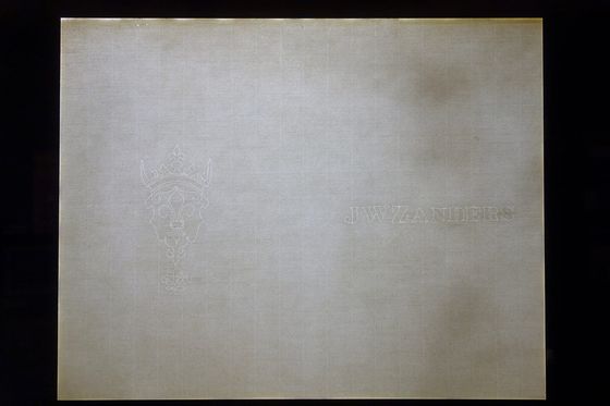 Sheet of laid paper on a light box showing a crowned crest watermark and a maker's name