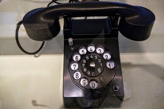 Black rotary dial desk telephone with the handset resting on its cradle