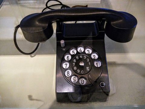 Black rotary dial desk telephone with the handset resting on its cradle