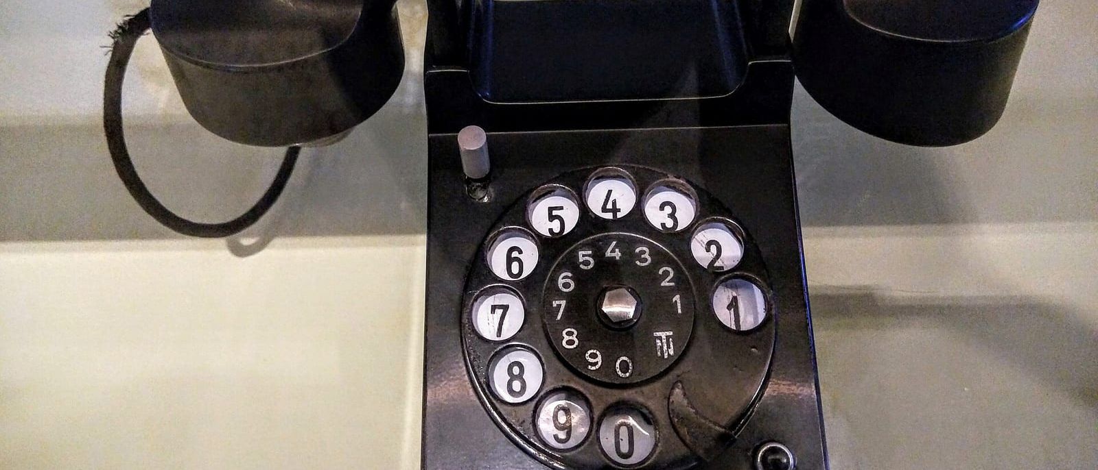 Black rotary dial desk telephone with the handset resting on its cradle