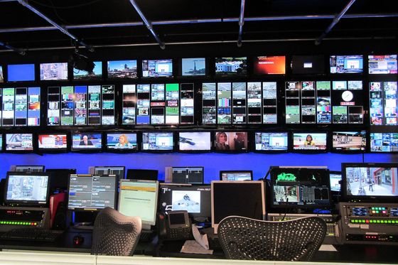 Wall of broadcast monitors and control desks in a television station control room