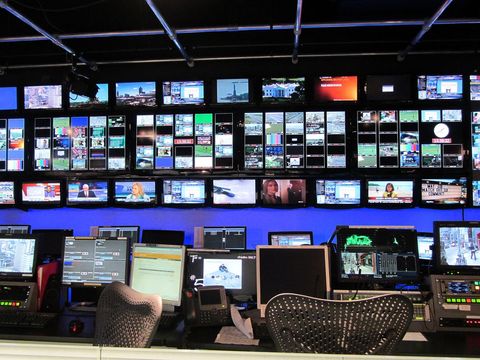 Wall of broadcast monitors and control desks in a television station control room